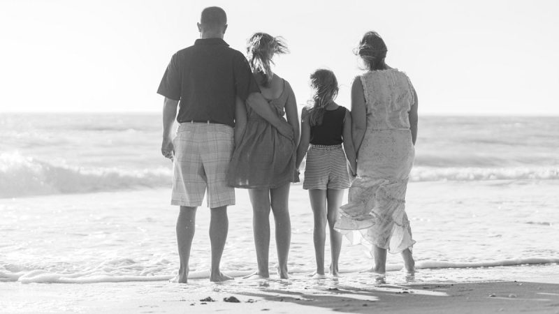 man and woman walking on beach during daytime